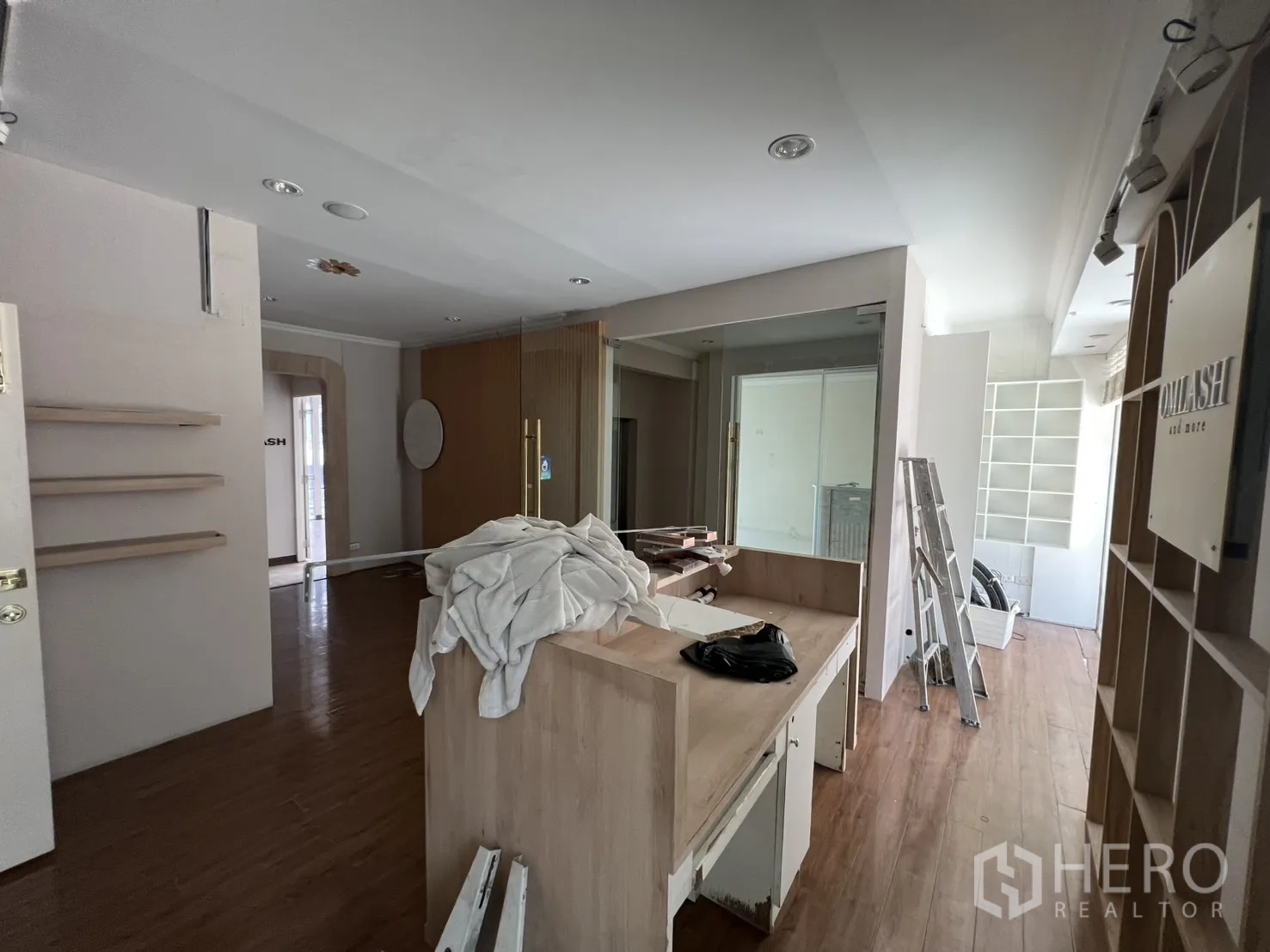 พื้นที่ขายปลีก ให้เช่า - โชว์รูมเปิดโล่งพร้อมโต๊ะไม้ ชั้นวาง และบันได ระหว่างฟิตเอาต์