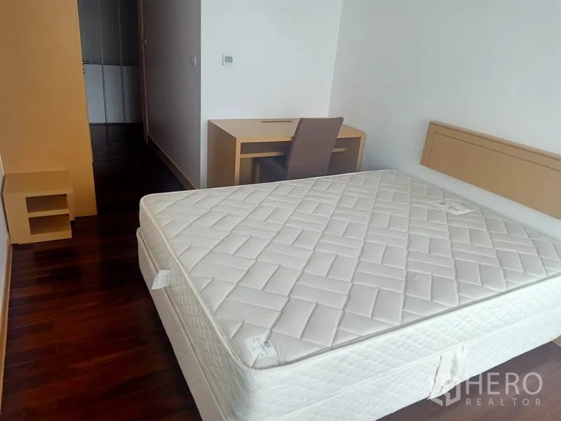 Condominium for rent in Watthana, Bangkok - Spacious bedroom with wood flooring, double bed, and a study desk.