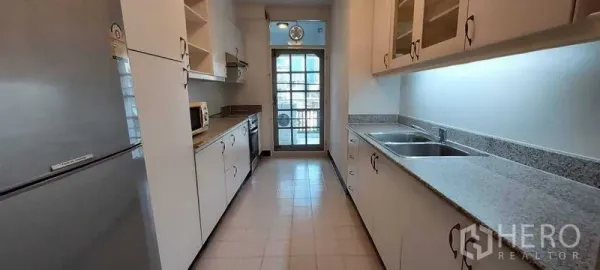 อพาร์ทเมนท์ ให้เช่าในPathum Wan, Bangkok - ครัวแบบแกลลีย์ ตู้สีขาว เคาน์เตอร์หินแกรนิต อ่างล้างจานคู่ และประตูกระจกออกระเบียง