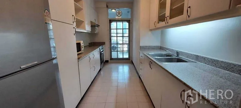 อพาร์ทเมนท์ ให้เช่าในPathum Wan, Bangkok - ครัวแบบแกลลีย์ ตู้สีขาว เคาน์เตอร์หินแกรนิต อ่างล้างจานคู่ และประตูกระจกออกระเบียง