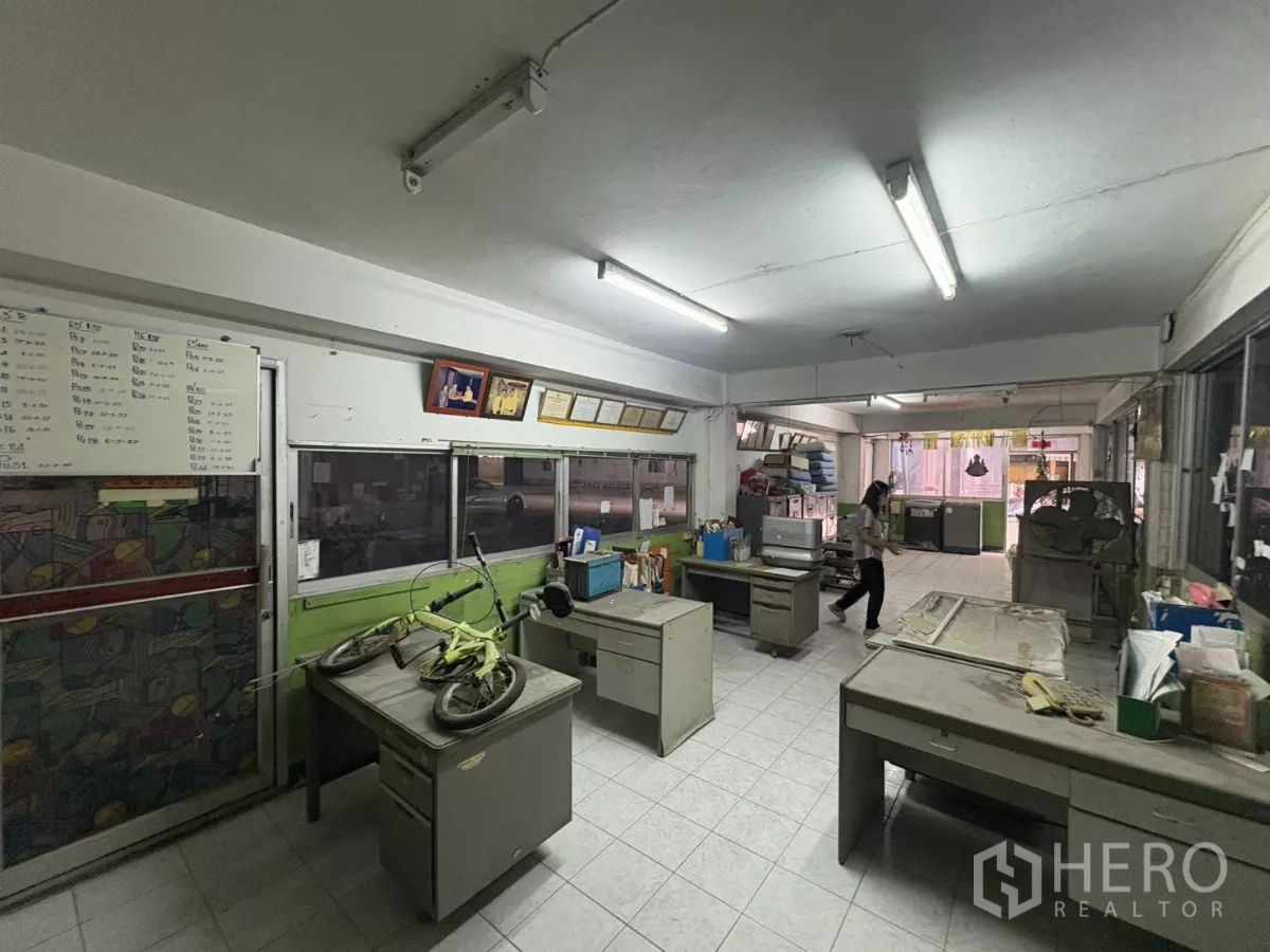 Warehouse for rent in Khlong Toei, Bangkok - Open‑plan office area with desks and a whiteboard beside windows.