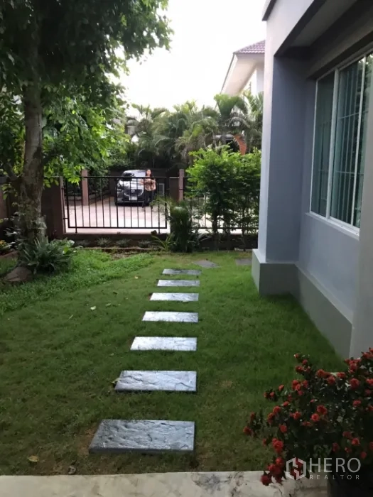 Detached House for rent in Saphan Sung, Bangkok - Lawn with stepping stones leading to the front gate and trimmed shrubs.