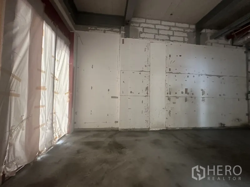 零售空间 出租在Khlong Toei, Bangkok - 侧墙贴补痕迹明显，窗面被遮挡的店内视角。