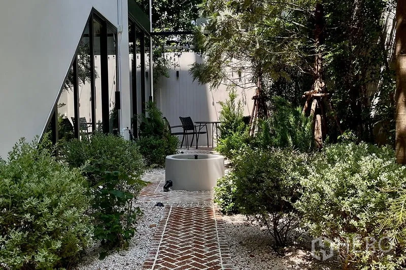 联排别墅 出售在Khlong Toei, Bangkok - 白天庭院，砖铺步道、繁茂绿植与圆形水景。