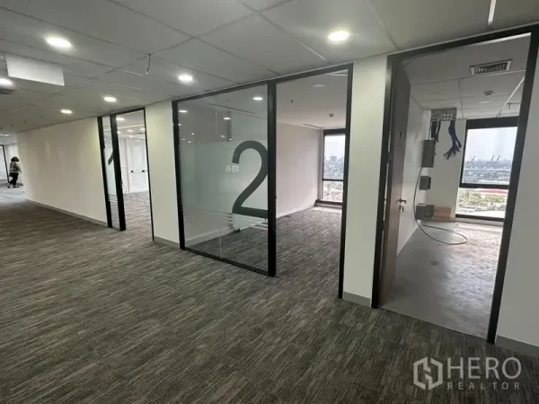 Office Space for rent in Khlong Toei, Bangkok - Corridor with numbered glass offices and a server room under installation, city view beyond.