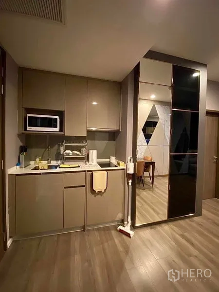 Condominium for rent in Phra Khanong, Bangkok - Compact modern kitchenette with glossy cabinets, sink and microwave.