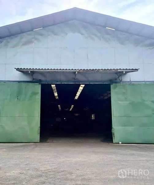 Warehouse for rent in Phra Pradaeng, Samut Prakan - Large green sliding doors on a gabled warehouse leading to deep storage space