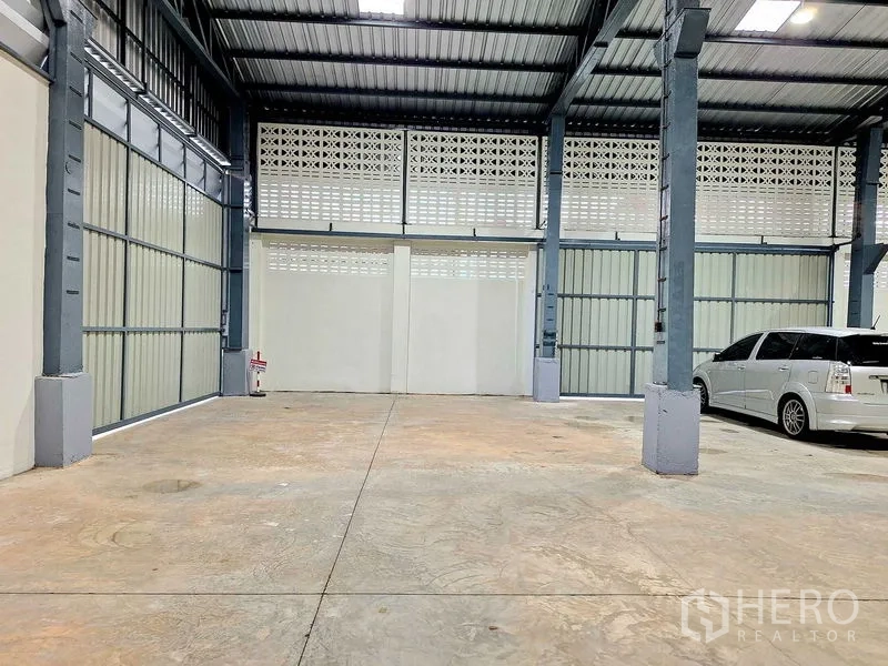 Warehouse for rent in Rat Burana, Bangkok - Indoor loading and parking area with metal sliding doors and clear open floor.