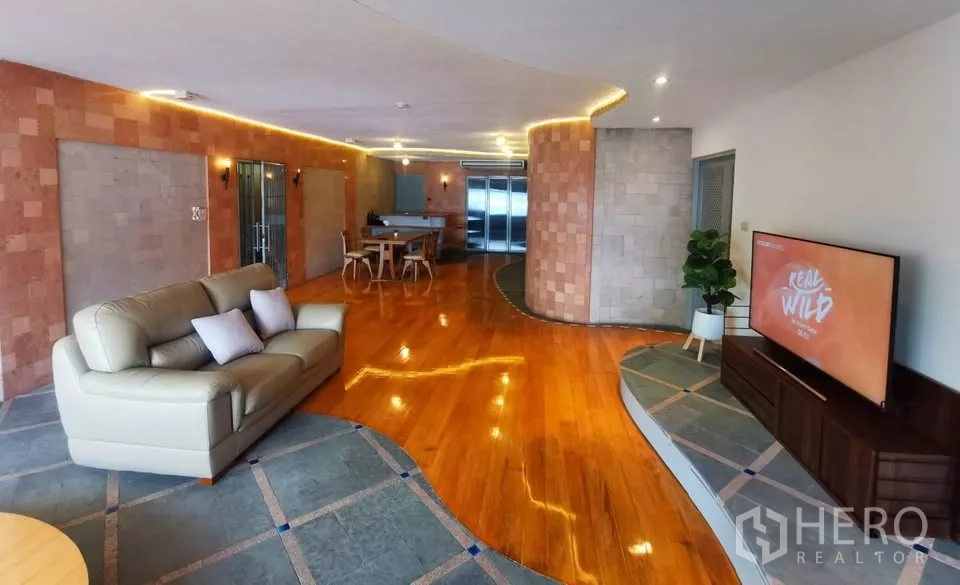 Condominium for rent in Pathum Wan, Bangkok - Open-plan living and dining area with wood floors, LED lighting, sofa and TV.