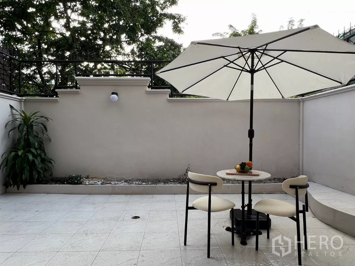Townhouse for rent - Private tiled courtyard with a large umbrella, round table and two chairs.