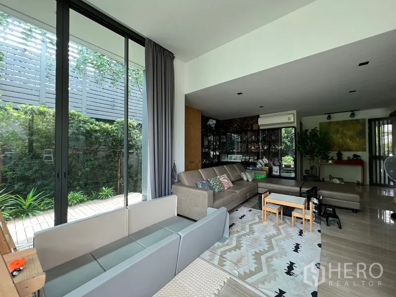 Detached House for sale in Bang Kapi, Bangkok - Lounge with marble floor, corner sofa and sliding doors to the patio.