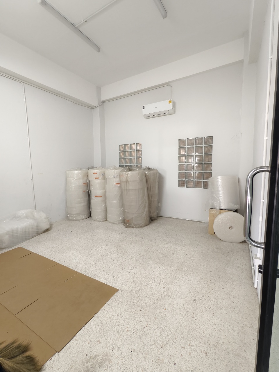 Warehouse for rent in Lat Krabang, Bangkok - Compact air-conditioned storage room with white walls, glass blocks, and LED lighting.
