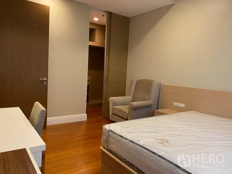 Condominium for rent in Khlong Toei, Bangkok - Second bedroom view toward closet and door, showing desk and armchair.