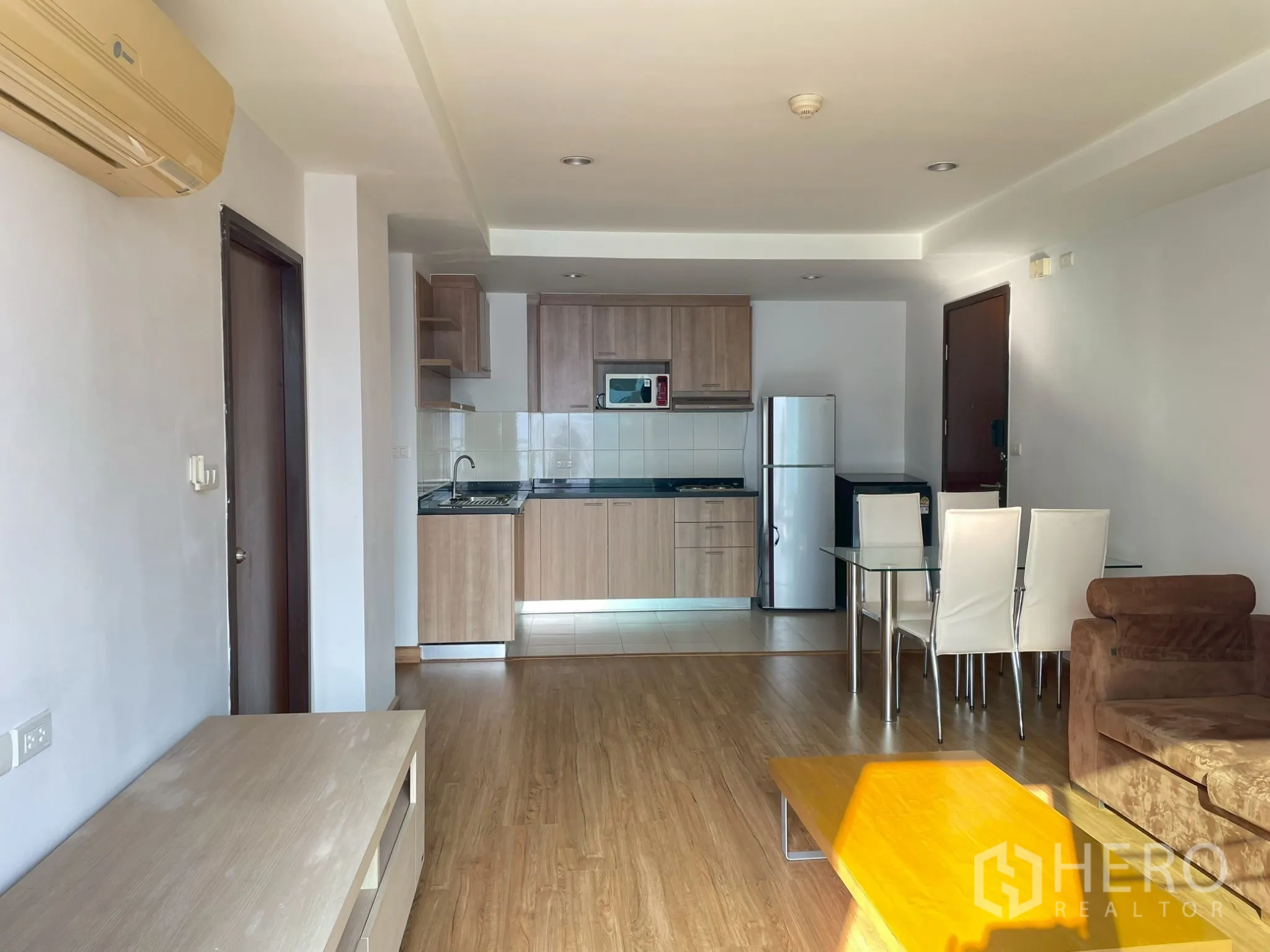 Apartment for rent in Khlong Toei, Bangkok - Open living area facing the kitchen with sofa, coffee table, and dining set.