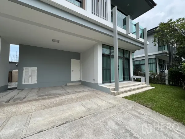 独立式住宅 出租在Bang Kapi, Bangkok - 车棚旁临落地窗与入户台阶，前院草坪整齐。