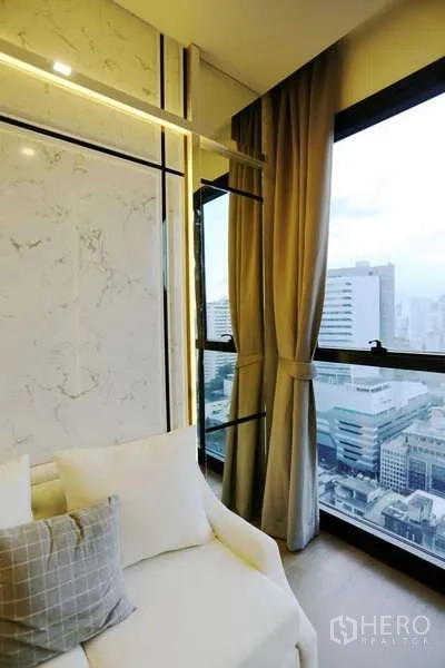 Condominium for rent in Watthana, Bangkok - Corner seating by panoramic window with sheer and blackout curtains and skyline outlook.