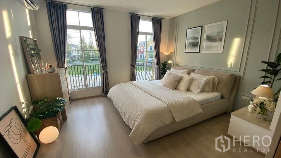 Townhouse for rent in Prawet, Bangkok - Spacious master bedroom with king bed, tall windows with curtains and garden outlook.