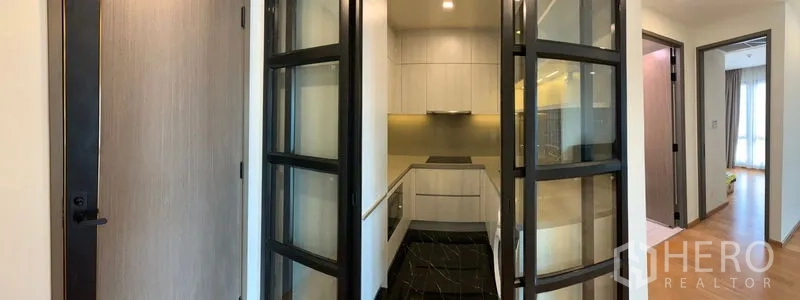 Condominium for sale in Khlong Toei, Bangkok - Glass folding doors opening to the enclosed kitchen from the corridor.
