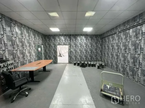 Factory for rent in Mueang Samut Prakan, Samut Prakan - Office room inside the factory with table, patterned walls and doorway to the yard.