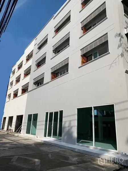 สำนักงาน ให้เช่าในHuai Khwang, Bangkok - อาคารสำนักงานสีขาวหลายชั้น พร้อมประตูกระจกชั้นล่างและลานปูพื้นหน้าตึก