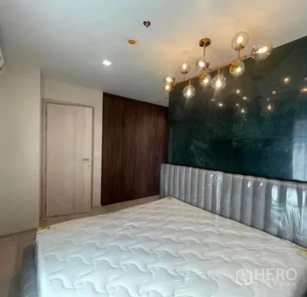 Condominium for rent or sale - Primary bedroom with dark green marble-style feature wall and chandelier above the bed.