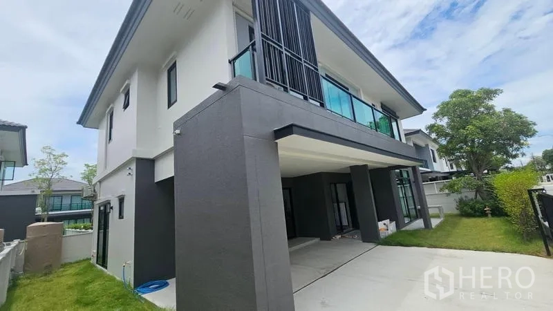 Detached House for rent in Bang Bo, Samut Prakan - Side view of the house showing covered parking and lawn.