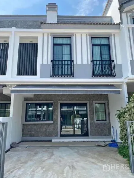 联排别墅 出租在Bang Phli, Samut Prakan - 现代两层联排外立面，带阳台栏杆与前院停车位。