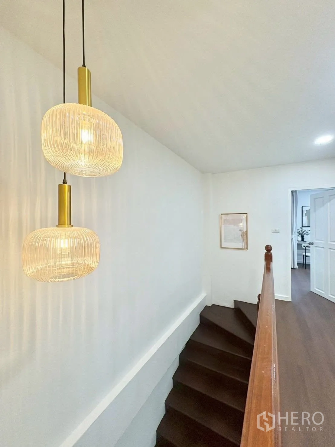 联排别墅 for rent in Huai Khwang, Bangkok - 深色木楼梯与扶手，搭配现代吊灯照明。