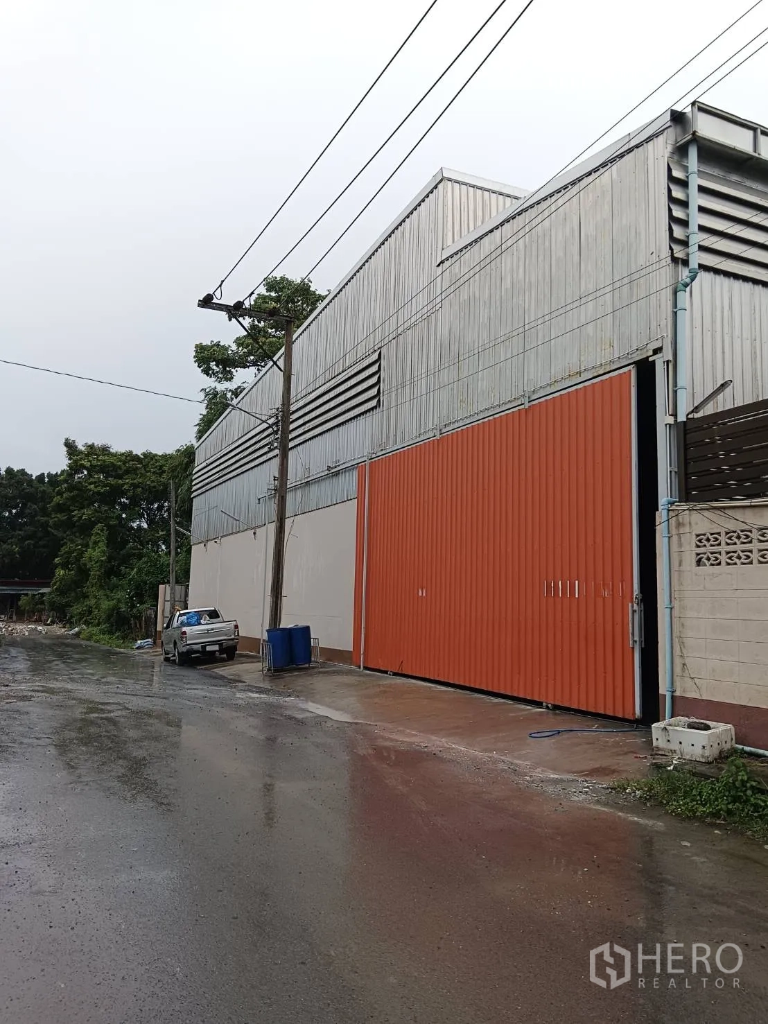 คลังสินค้า ให้เช่าในKhlong Sam Wa, Bangkok - มุมมองหน้าโกดังผนังเมทัลชีทพร้อมประตูสไลด์สีส้ม ในเขตคลองสามวา กรุงเทพฯ