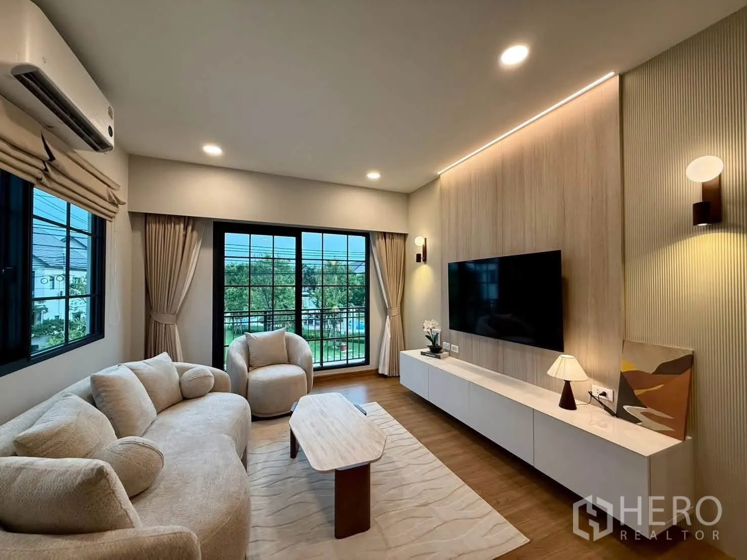 独栋房屋 for rent in Bang Phli, Samut Prakan - 客厅配沙发组合、电视墙、落地推拉门与空调。