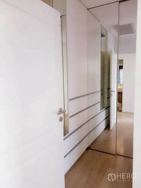 คอนโด ให้เช่าในBangkok - โถงทางเดินสว่างพร้อมตู้บิวท์อินสีขาวและบานกระจกในคอนโด