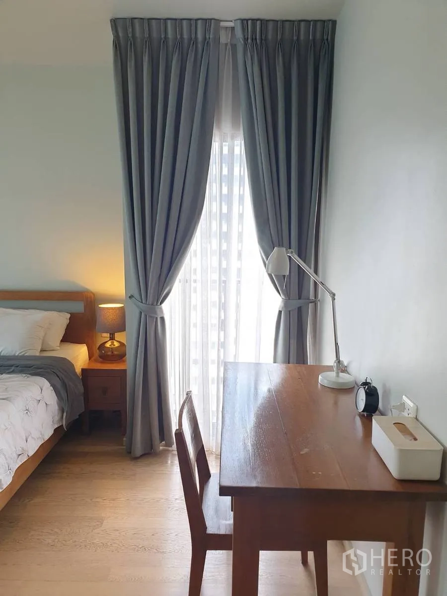 คอนโด ให้เช่าหรือขายในBangkok - โต๊ะทำงานและเก้าอี้ข้างหน้าต่างติดผ้าม่านในห้องนอน
