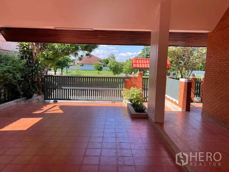 Detached House for rent in Bang Phli, Samut Prakan - Covered carport with terracotta tiles opening to the front gate and lake view.