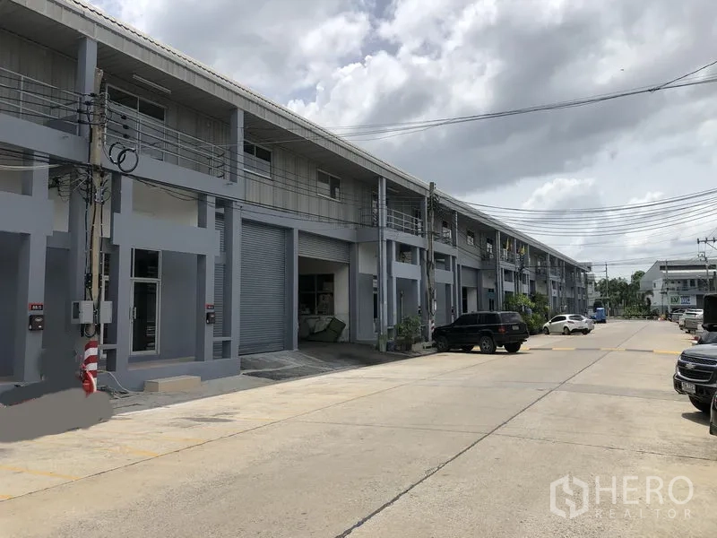 Factory for rent in Pak Kret, Nonthaburi - Wide internal road with parking bays in an industrial estate outside the factory units.