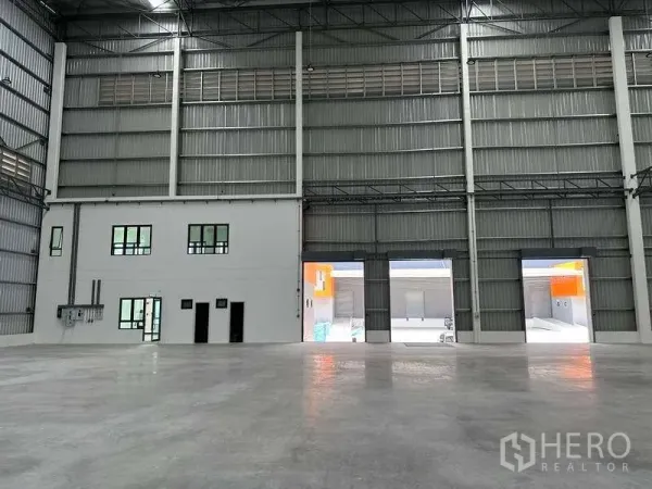 工厂 出租在Bang Phli, Samut Prakan - 仓库墙面带两层办公室，装卸口通向外部作业区。