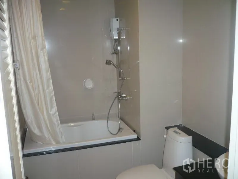 公寓 出租在Khlong Toei, Bangkok - 现代浴室，浴缸与淋浴一体，配马桶，浅色墙面。