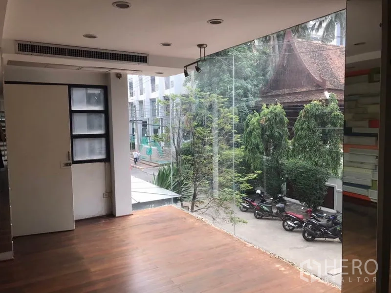 零售空间 出租在Watthana, Bangkok - 二层木地板展示区，落地玻璃俯瞰街景与绿树