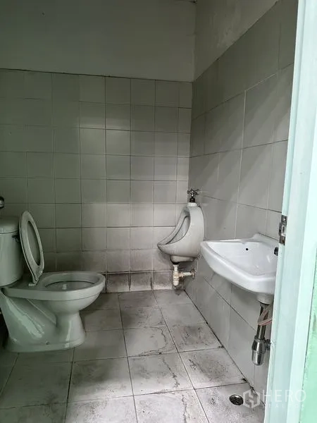 Factory for rent in Bang Bo, Samut Prakan - Tiled restroom with toilet, urinal, and sink inside the factory facility.