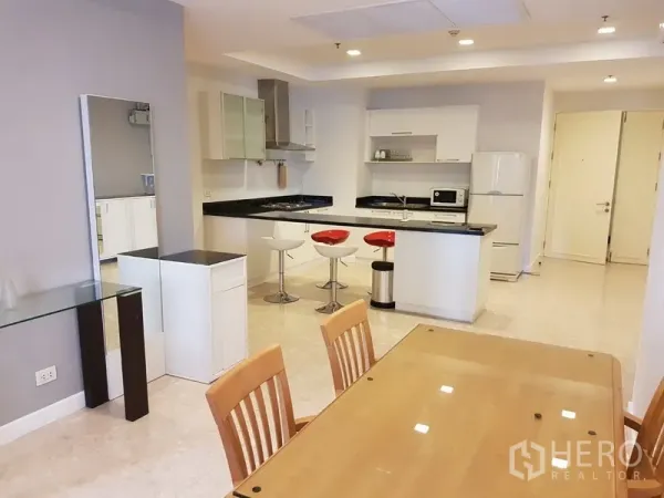 คอนโด ให้เช่าในKhlong Toei, Bangkok - ครัวแบบเปิดพร้อมตู้สีขาว เคาน์เตอร์หินสีดำ ไอส์แลนด์บาร์พร้อมสตูลสีแดง และพื้นที่รับประทานอาหารถัดกัน