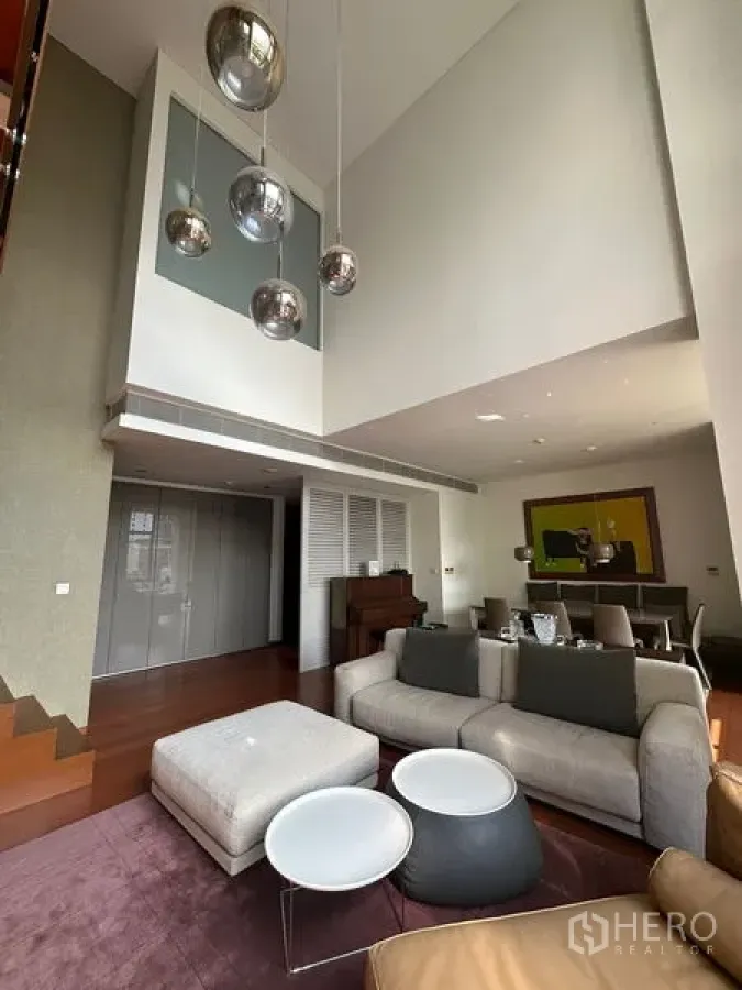Condominium for rent or sale in Sathon, Bangkok - Wide shot of double-height lounge flowing to the dining area with contemporary lighting.