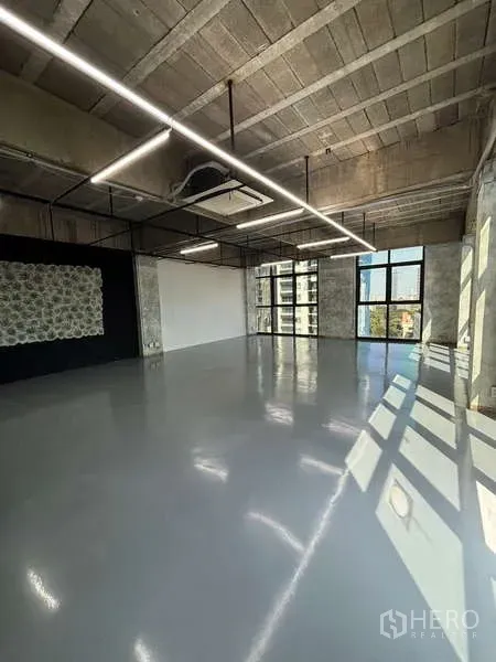 Office Space for rent - Loft-style office interior with natural light, black feature wall and ceiling grid lighting.
