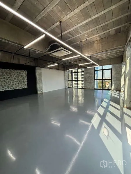 Office Space for rent - Loft-style office interior with natural light, black feature wall and ceiling grid lighting.