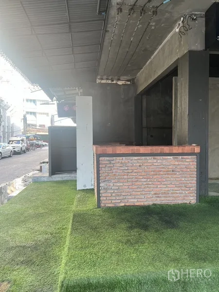 零售空间 出租在Watthana, Bangkok - 近距离拍摄的推拉门入口，通向雨棚下的混凝土房间