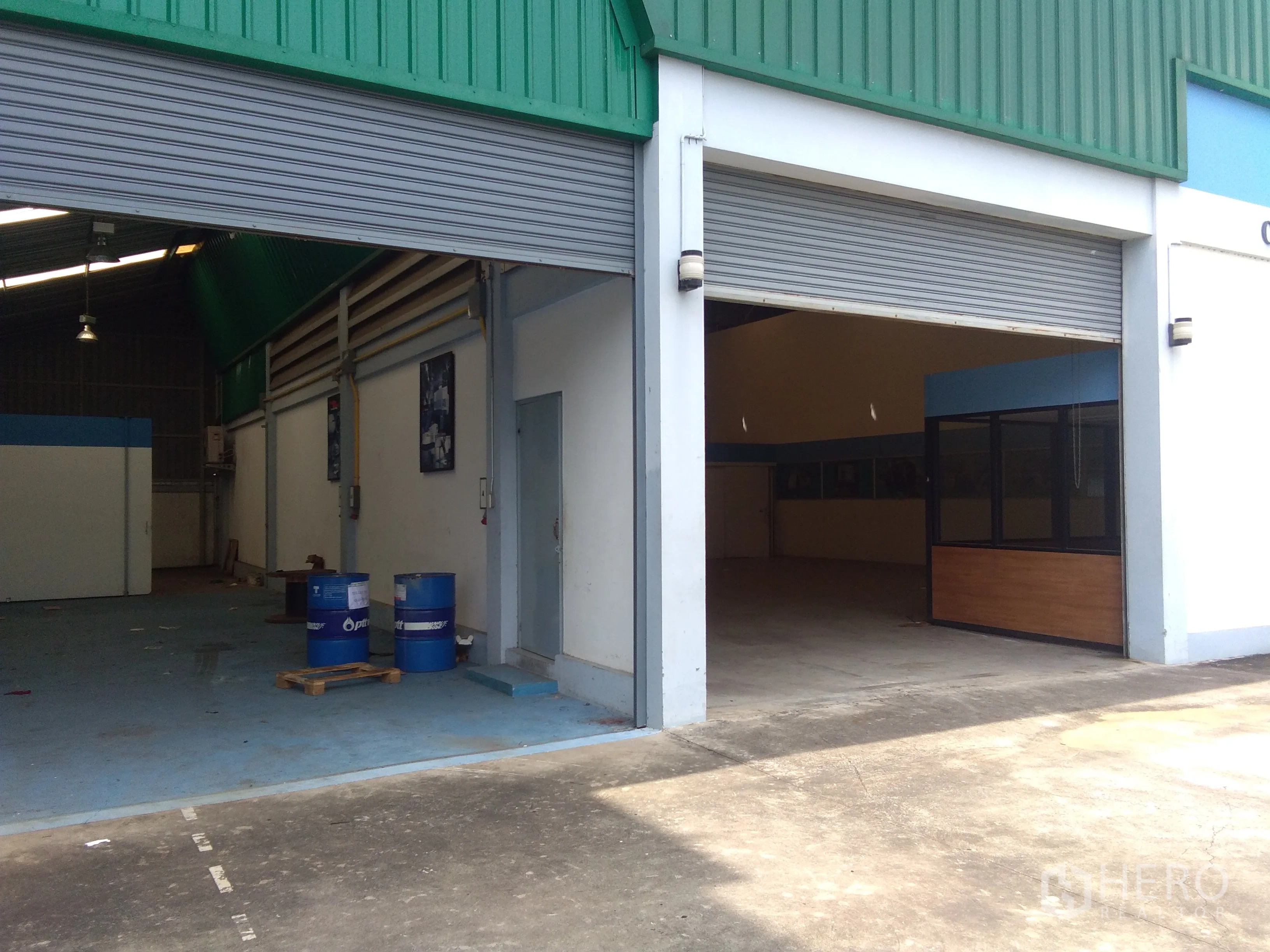 Factory for sale in Lam Luk Ka, Pathum Thani - Exterior of an industrial factory with twin roller shutter doors and a covered loading area.