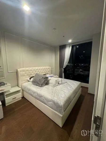 คอนโด ให้เช่าในKhlong Toei, Bangkok - ห้องนอนอบอุ่น เตียงบุหนัง โต๊ะข้างเตียง และวิวเมืองยามค่ำคืน