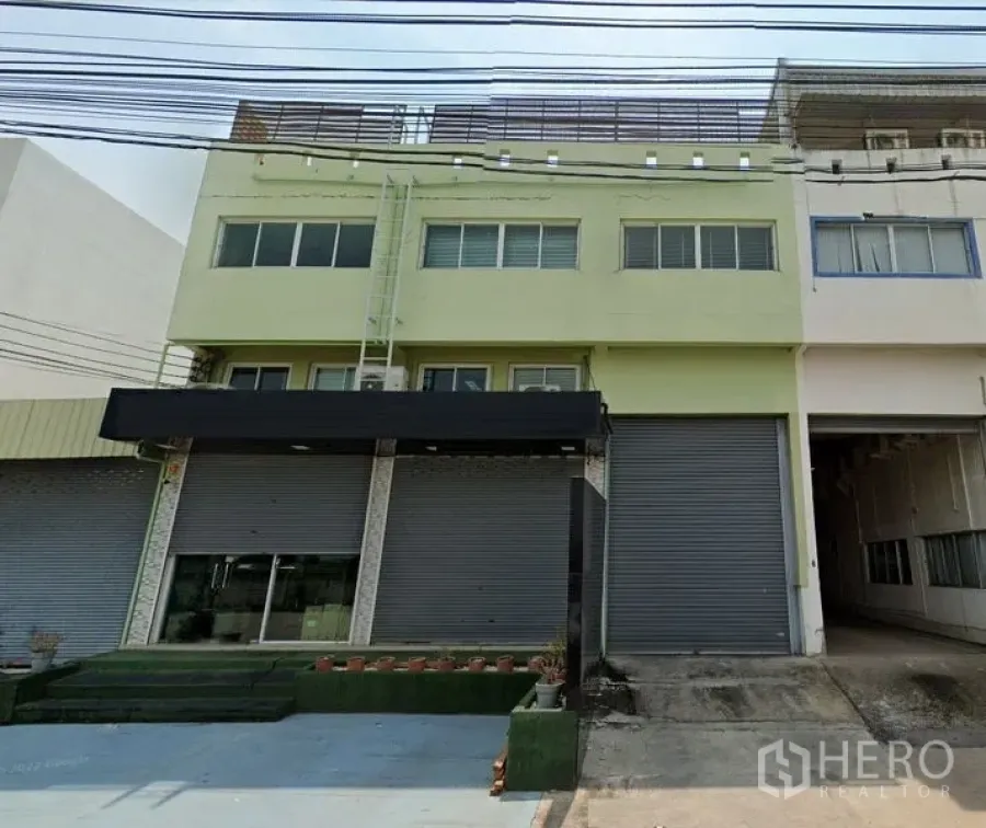 货栈 出租在Samut Prakan - 三层仓库外立面，卷帘门与装卸雨棚