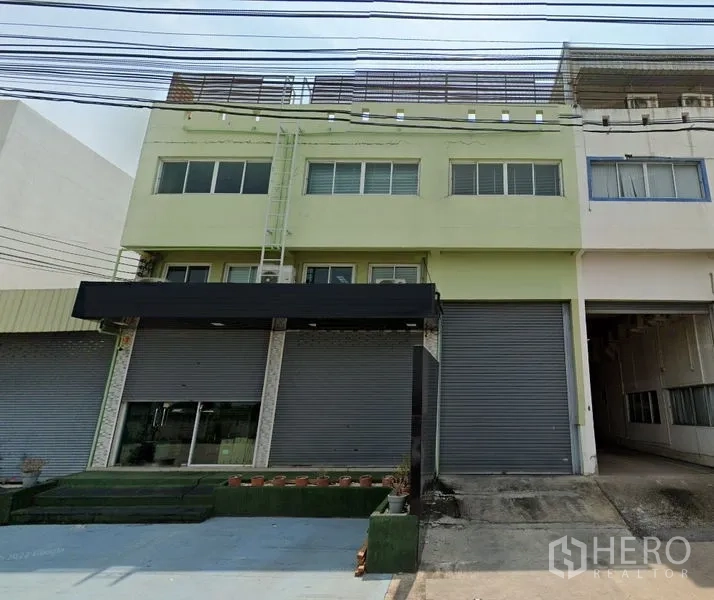 货栈 出租在Samut Prakan - 三层仓库外立面，卷帘门与装卸雨棚
