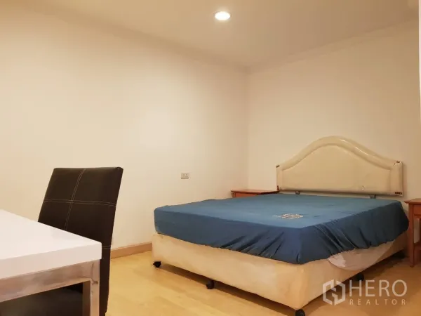 公寓 出租在Khlong Toei, Bangkok - 次卧配蓝色床、书桌和嵌灯，木地板