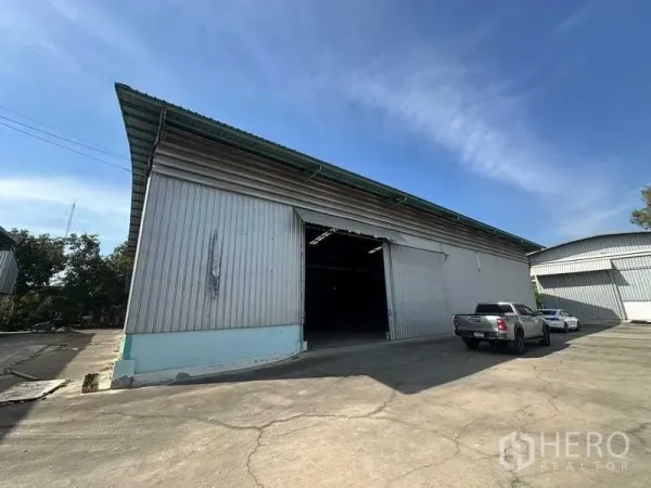 货栈 出租在Phra Nakhon Si Ayutthaya - 仓库正面，大型推拉门与卡车停车区一览。