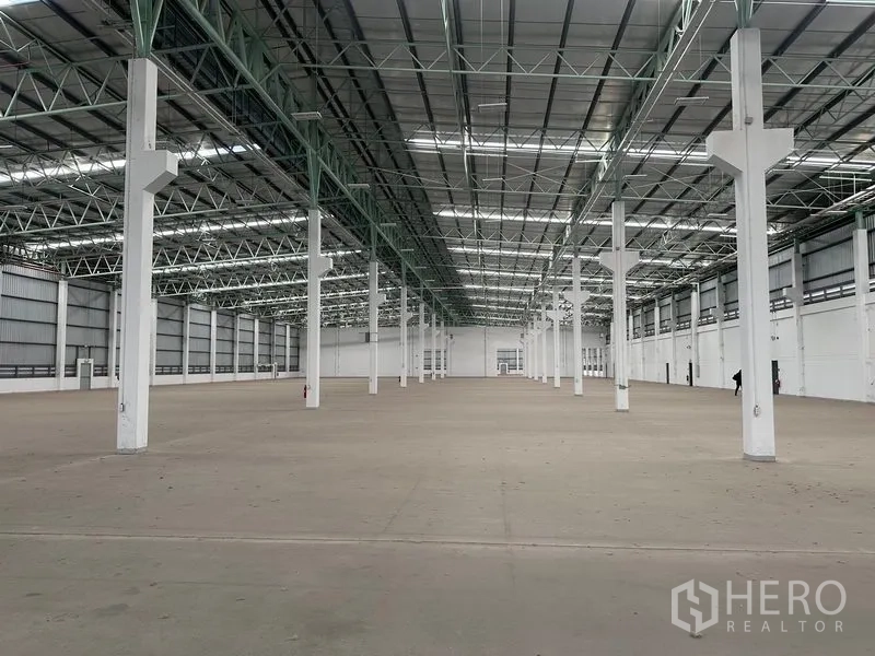 工厂 出租在Bang Sao Thong, Samut Prakan - 宽阔仓库内部，高挑钢桁架屋顶与成排立柱